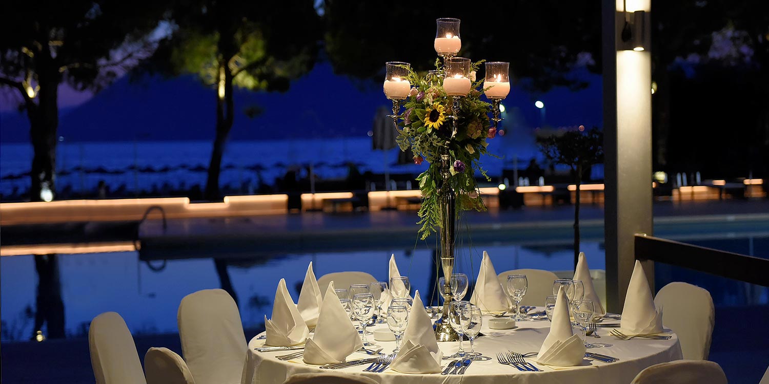 Στολισμός Εταιρικής Εκδήλωσης για τα 130 Χρόνια της Εφημερίδας «Πελοπόννησος» 17 Λεπτομέρεια του επετειακού ανθοστολισμού σε επίσημο τραπέζι με φόντο το απέραντο γαλάζιο στο Porto Rio