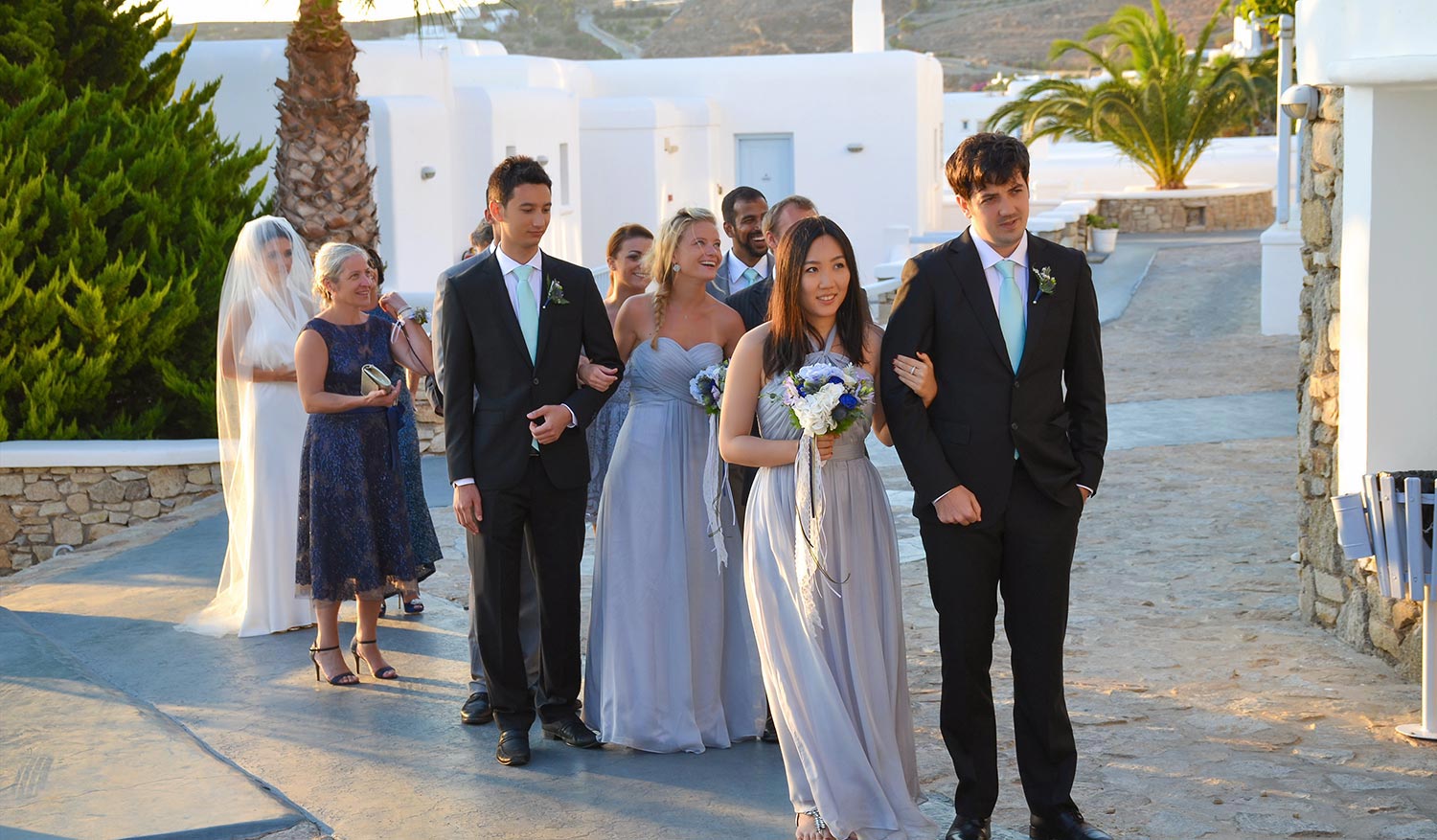 Mykonos | Japanese-Romanian Destination Wedding 15 Elegant Japanese Romanian wedding procession walking through the Saint John resort in Mykonos, planned by Rogdaki Events