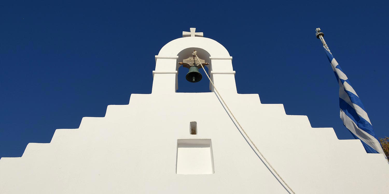 Mykonos | Japanese-Romanian Destination Wedding 3 Mykonos Saint John chapel with Greek flag, elegant Japanese Romanian wedding venue by Rogdaki Events, Cycladic romance paradise